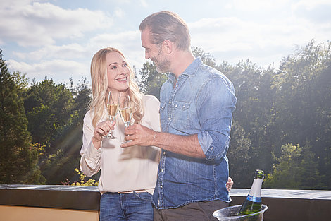 Paar stoßt auf Terrasse an 